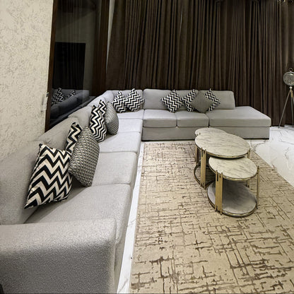 A modern and elegant living room featuring a grey L-shaped sofa and marble-top coffee tables.