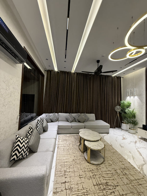 A modern and elegant living room featuring a grey L-shaped sofa and marble-top coffee tables.