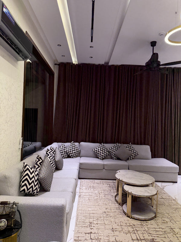 A modern and elegant living room featuring a grey L-shaped sofa and marble-top coffee tables.