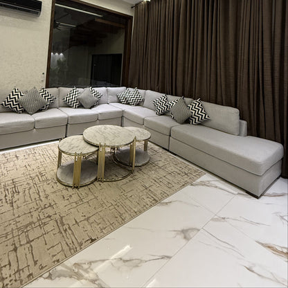 A modern and elegant living room featuring a grey L-shaped sofa and marble-top coffee tables.