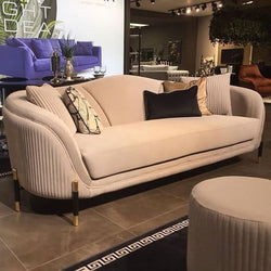 Beige velvet sofa
Modern curved sofa
Luxury living room furniture
Gold leg sofa
Elegant sofa design
Fluted detail sofa
Velvet couch with pillows
High-end upholstered sofa
Contemporary sofa set
Showroom sofa display