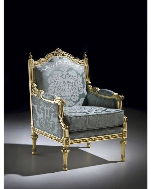 A highly ornate French Louis XV style armchair with a gilded gold carved wooden frame and upholstered in a luxurious blue and grey patterned damask fabric,