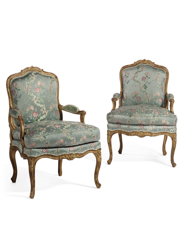 A pair of ornate Louis XV style Bergère chairs with gilded carved wooden frames and upholstered in a light green floral patterned fabric