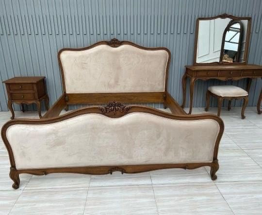 An elegant bed set featuring a wooden frame and upholstered headboard, accompanied by matching furniture.