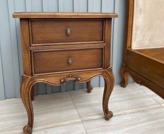 A wooden two-drawer nightstand with a classic design.