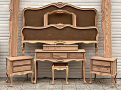 A wooden Baroque-style bedroom set, including a bed frame, nightstands, and a dressing table.